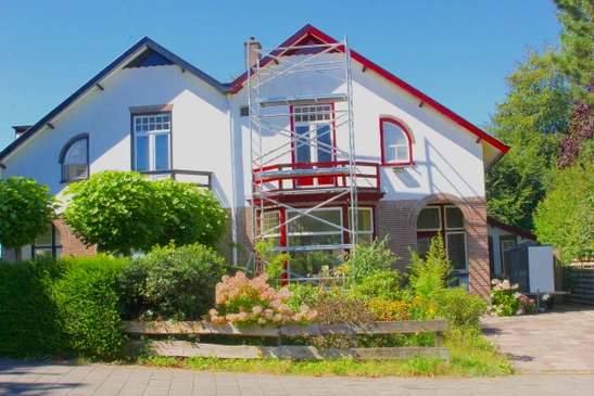 Sc&egrave;ne ext&eacute;rieure montrant une maison r&eacute;sidentielle avec &eacute;chafaudage m&eacute;tallique install&eacute; en fa&ccedil;ade pour travaux de r&eacute;novation