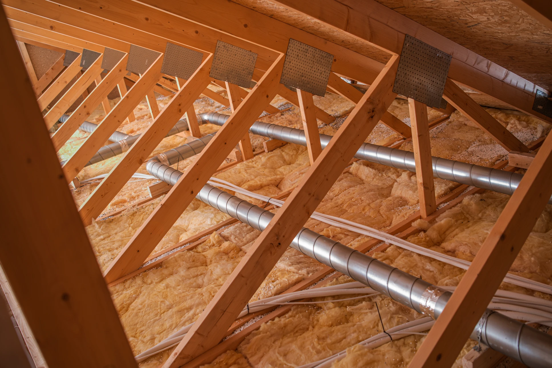 Homme en pull vert appliquant un produit de protection sur bardage bois extérieur d'une maison avec pinceau
