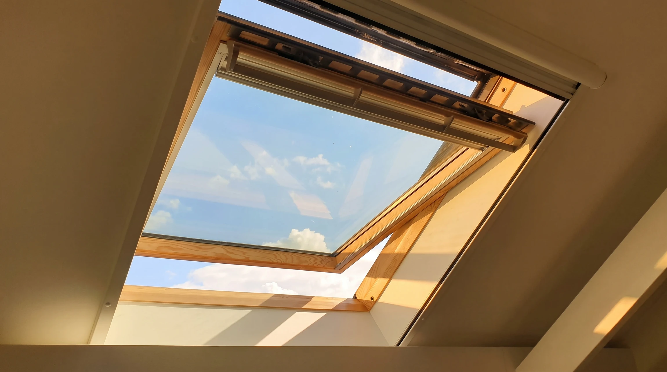 Portrait d'une fenêtre ouverte de lucarnes dans un toit en ardoise par jour ensoleillé, avec un ciel bleu et des nuages blancs