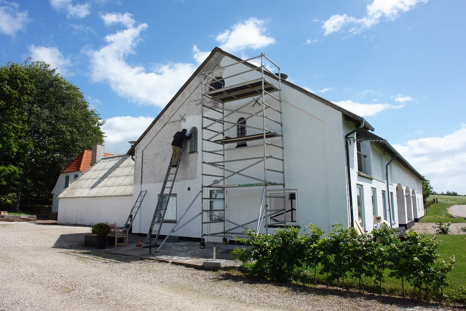 Constructeur enduisant des murs extérieurs avant de peindre la façade extérieure de la maison