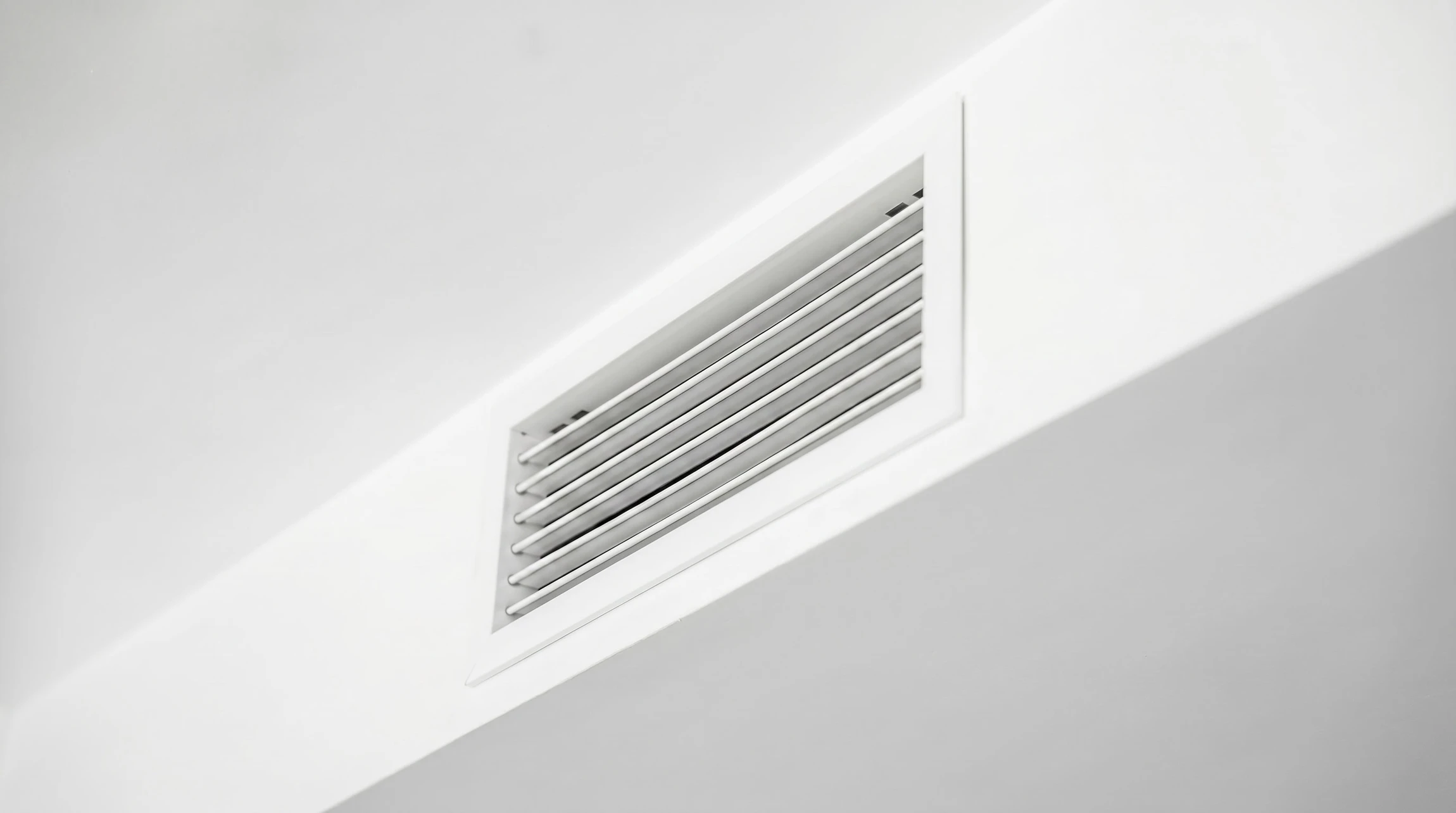 Un technicien en tenue de travail bleue installe des conduits de ventilation dans un local technique